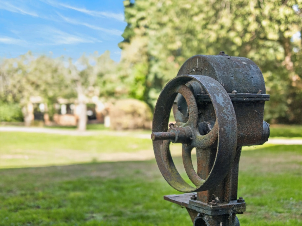 Antique cast iron garden machinery with lawns and trees at Loddon Hall, Norfolk