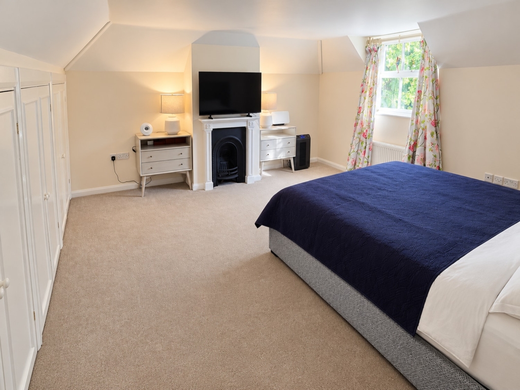 Bedroom with double bed, fireplace and fitted wardrobes in Loddon Hall Cottage, Norfolk