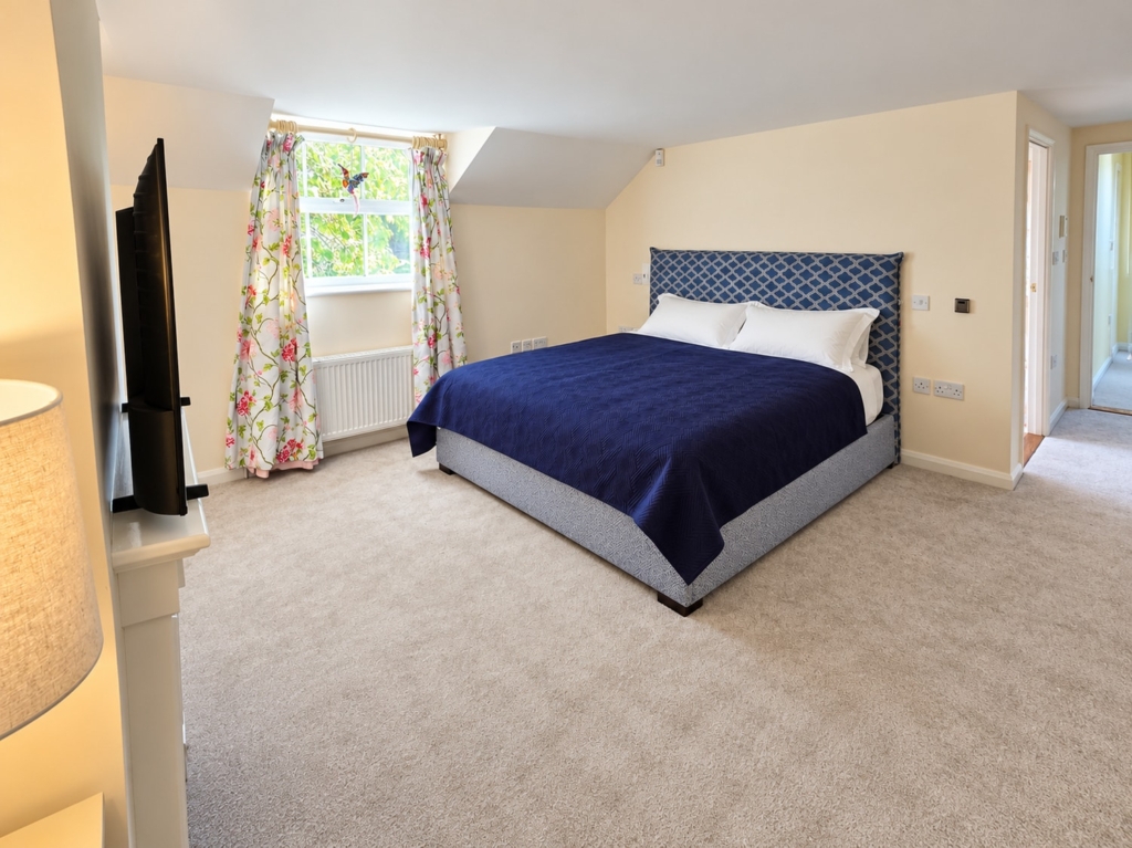 Double bedroom with floral curtains and garden view in Loddon Hall Cottage, Norfolk