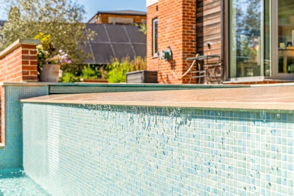 Water spills gently over the mosaic-tiled pool edge in the sunshine.