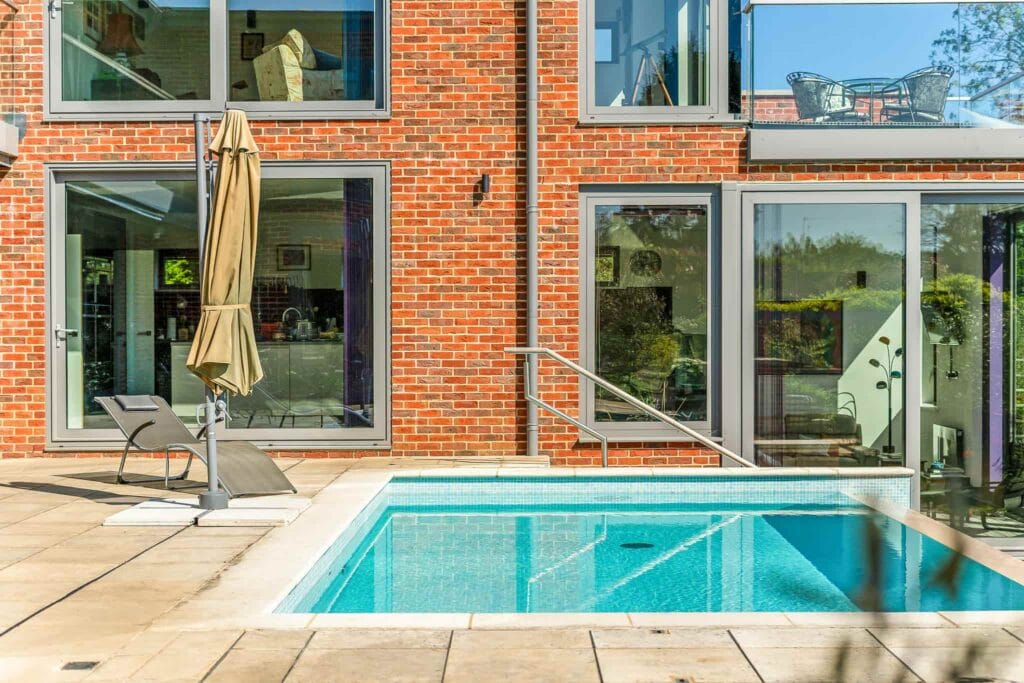 Sleek poolside lounger beside sparkling blue water for serene relaxation.