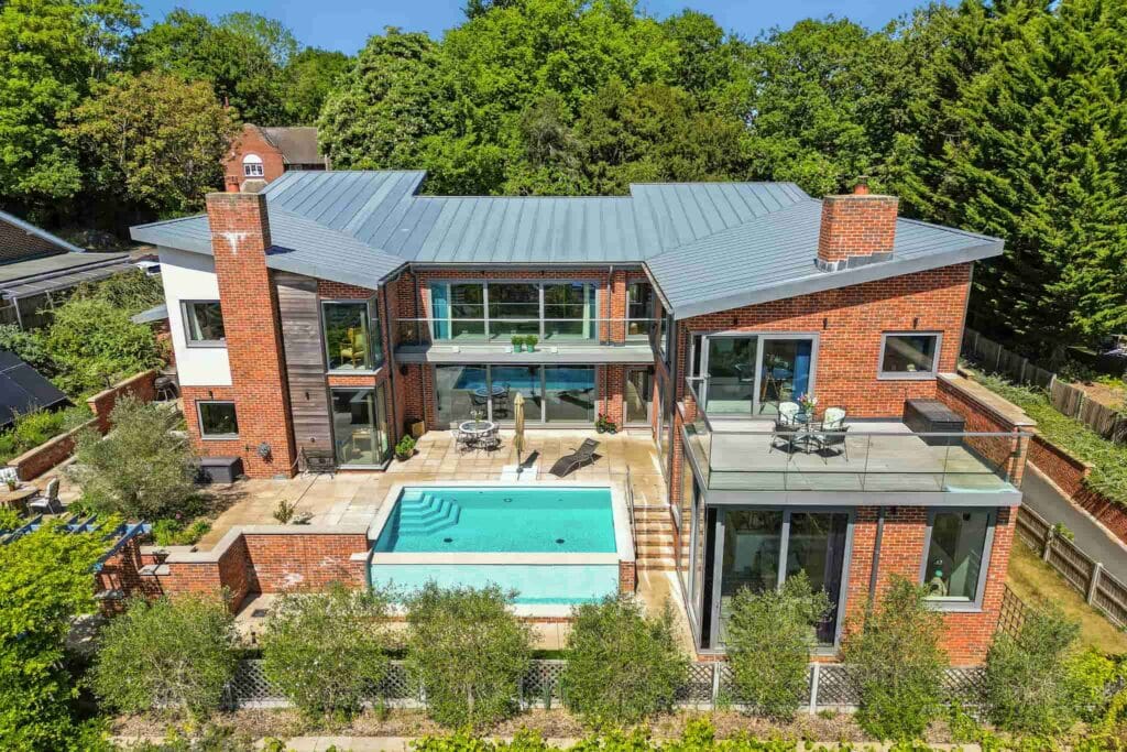 A striking modern retreat embraced by lush greenery, with a central sun-kissed pool and terraces designed for luxurious outdoor living and serene privacy.