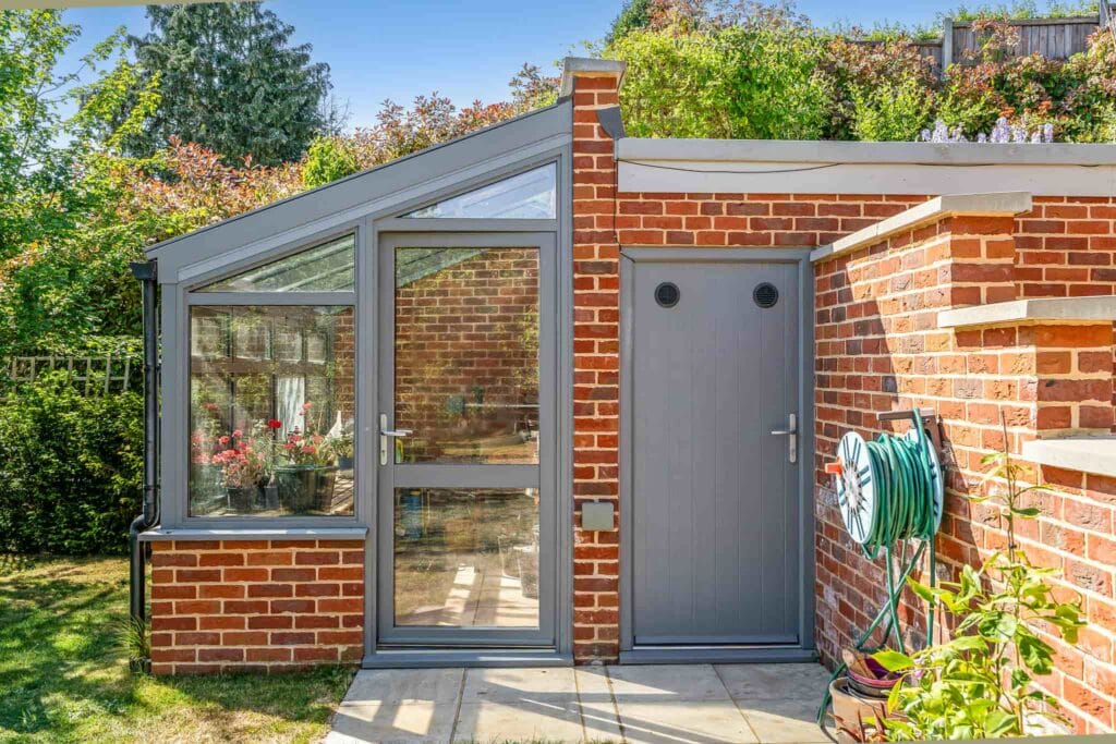 Charming brick and glass greenhouse with adjoining garden store.