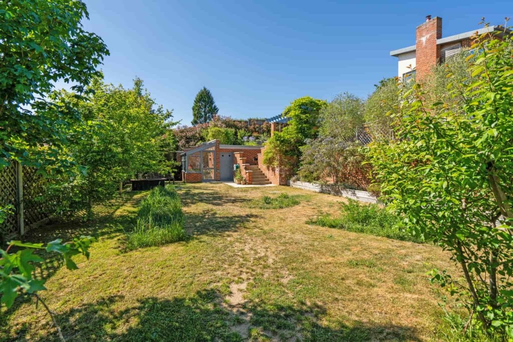 Lawn garden leading to a greenhouse and terraced entertaining space.