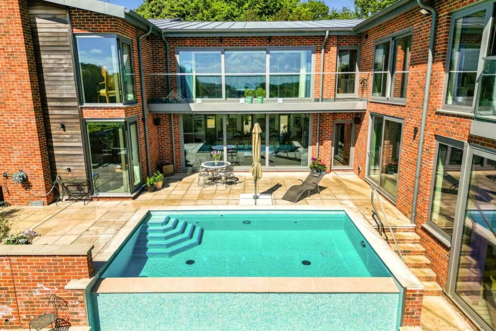 A sunlit courtyard oasis with sparkling pool and inviting loungers, perfect for leisurely afternoons and tranquil summer escapes.