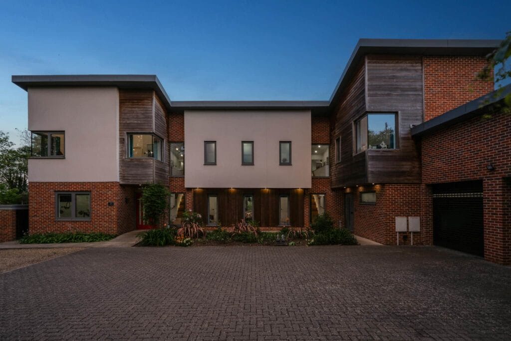 Striking contemporary façade illuminated by the soft glow of evening lights, creating a warm and welcoming sense of arrival.