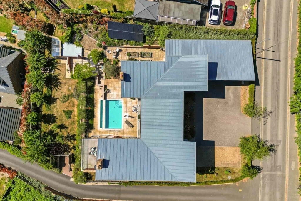 Aerial view showcasing the home’s striking architecture, private pool, and beautifully landscaped grounds.