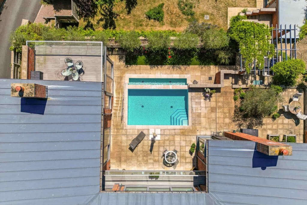 Aerial view of the sunlit courtyard with pristine pool, framed by terraces for relaxing and entertaining.