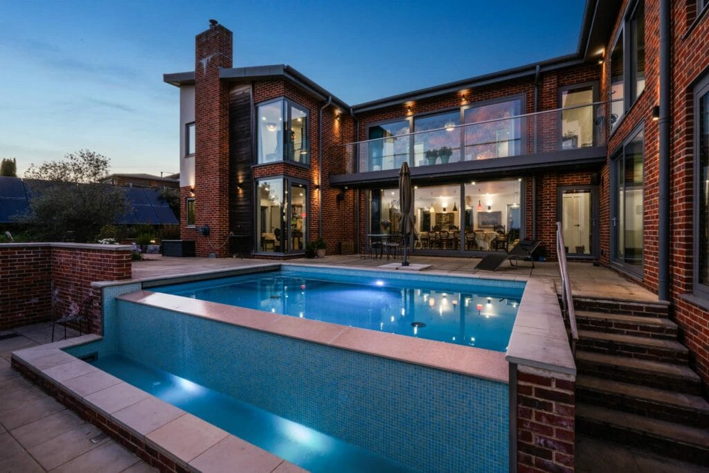 Illuminated infinity pool and patio at dusk, creating a serene resort-style retreat for evening relaxation and entertaining.