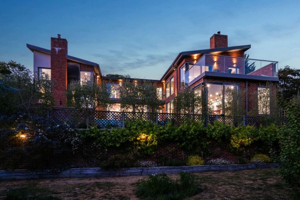 Striking rear elevation with glass-fronted balconies and warm evening lighting.