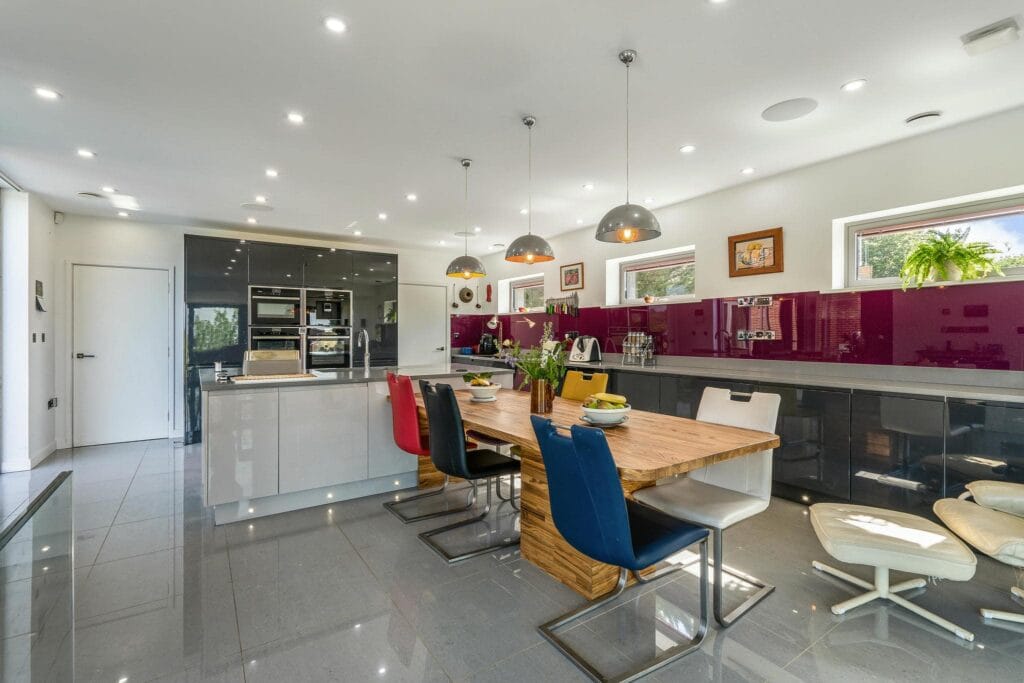 Spacious contemporary kitchen with high-gloss cabinetry, a large central island, and vibrant dining area seating.