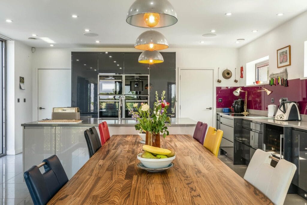Kitchen dining area with a vibrant mix of seating, sleek cabinetry, and bold accent splashback.