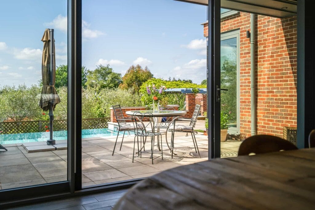 Charming dining room outlook to the sun-drenched terrace, where a bistro table overlooks the shimmering pool and lush garden.