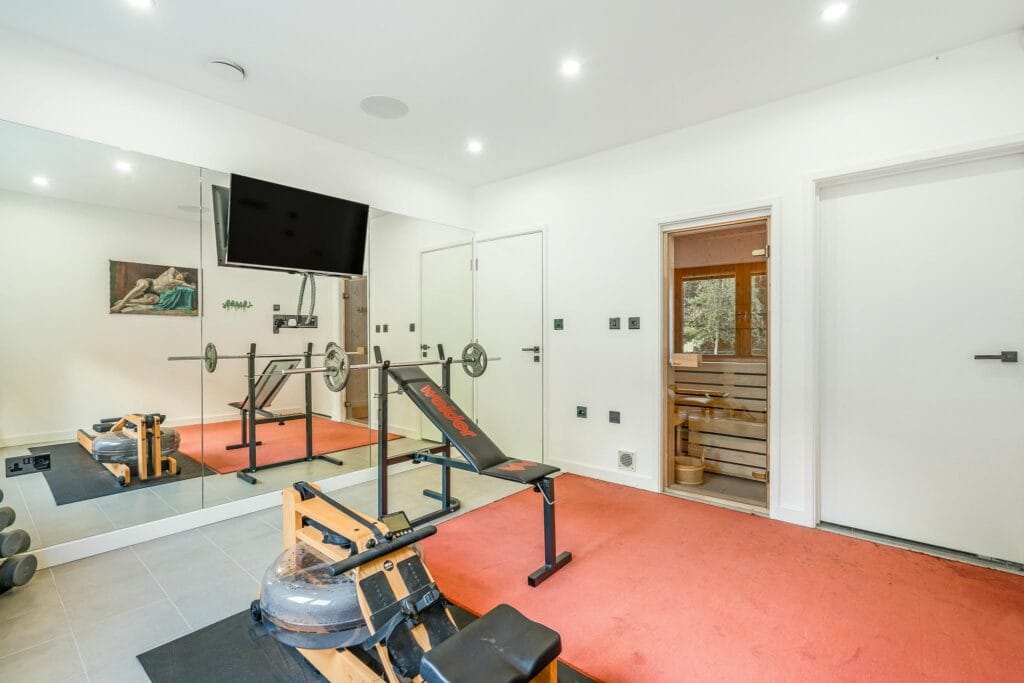 Private gym with mirrored walls, adjoining sauna, and shower room for the ultimate at-home wellness experience.