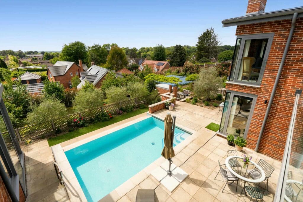 Balcony view from the principal bedroom overlooking the sunlit pool and landscaped gardens.
