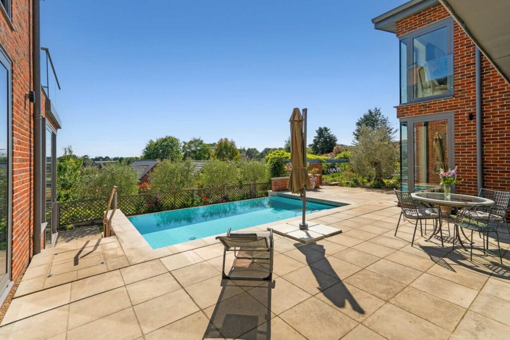 Sunlit pool terrace with dining and lounging space for relaxed summer days.