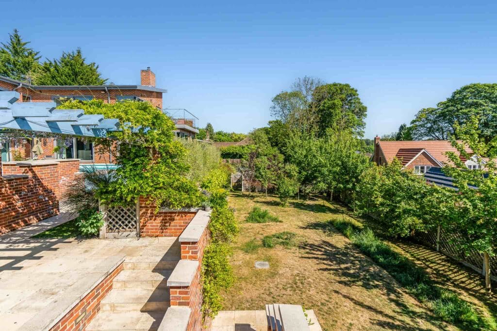 Sunlit terraced steps leading to a private, tree-lined garden.