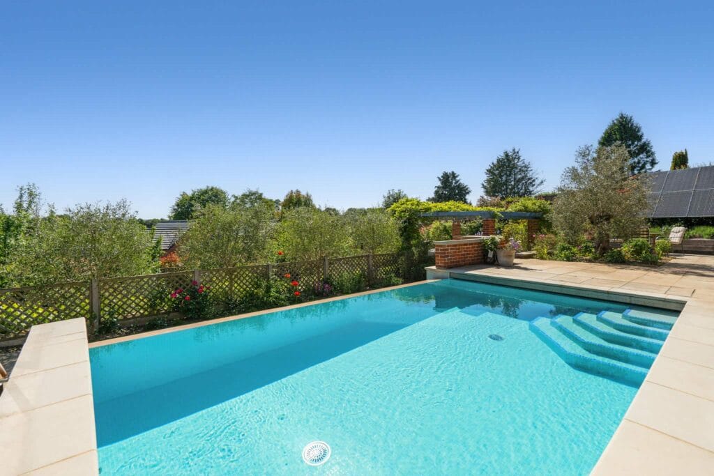 Inviting infinity pool framed by vibrant gardens and endless blue skies.