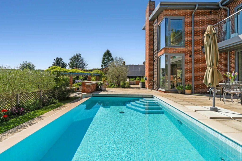 Sparkling turquoise pool leading to sunlit terraces surrounded by lush gardens.