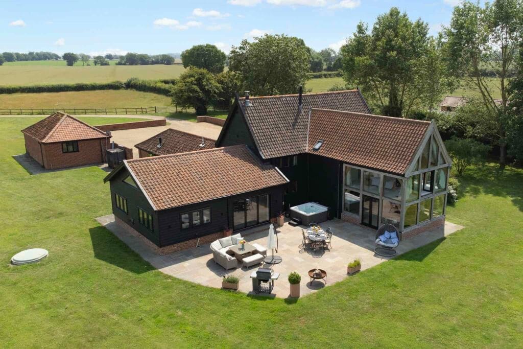 Aerial view of Upper Barn showing the oak-framed gable, patio with hot tub and Norfolk countryside