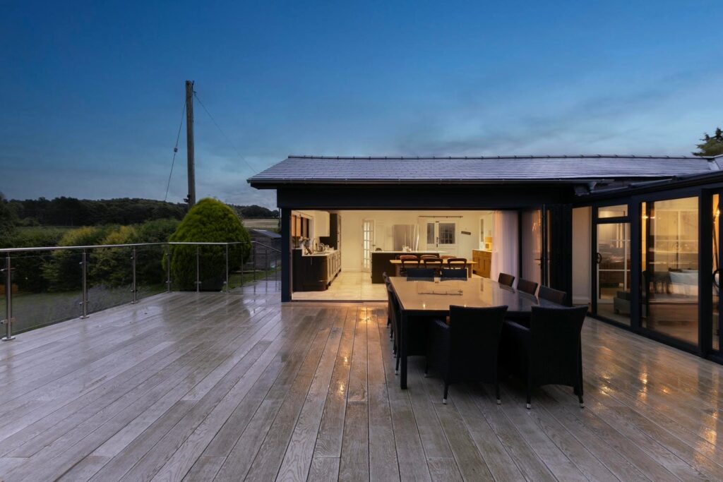 Evening terrace dining with illuminated kitchen backdrop