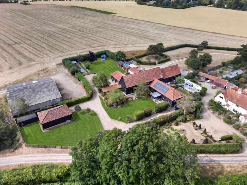 Aerial view of The Tithe Barn Sisland showing main barn, holiday barns, gravel drive, and surrounding Norfolk farmland