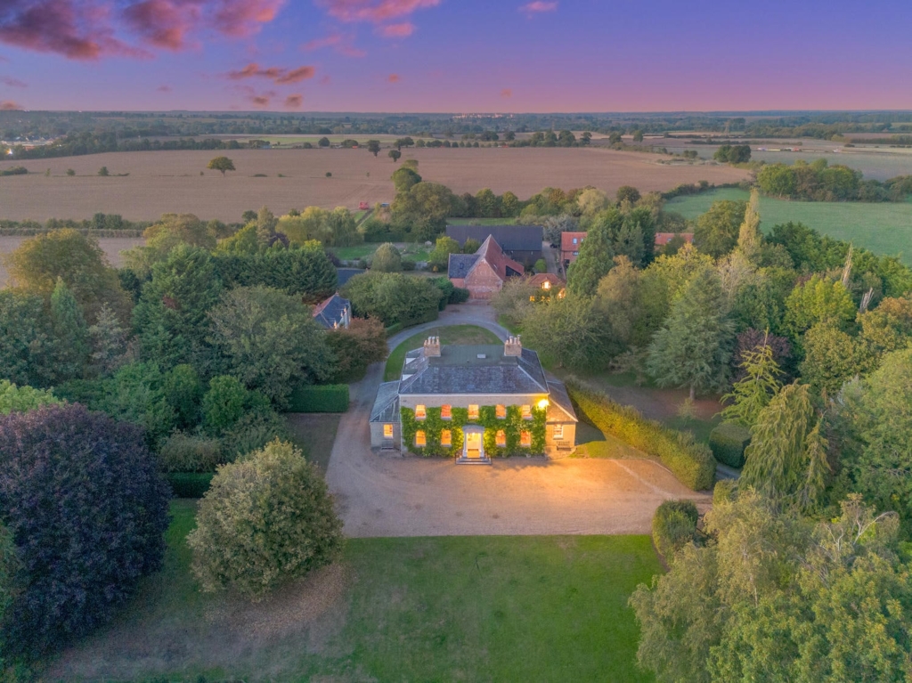 Aerial view of Loddon Hall at dusk with gravel drive, gardens and Norfolk countryside