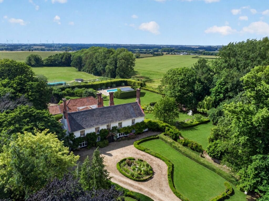 Aerial view of Bury's Hall with pool, gardens and Norfolk countryside
