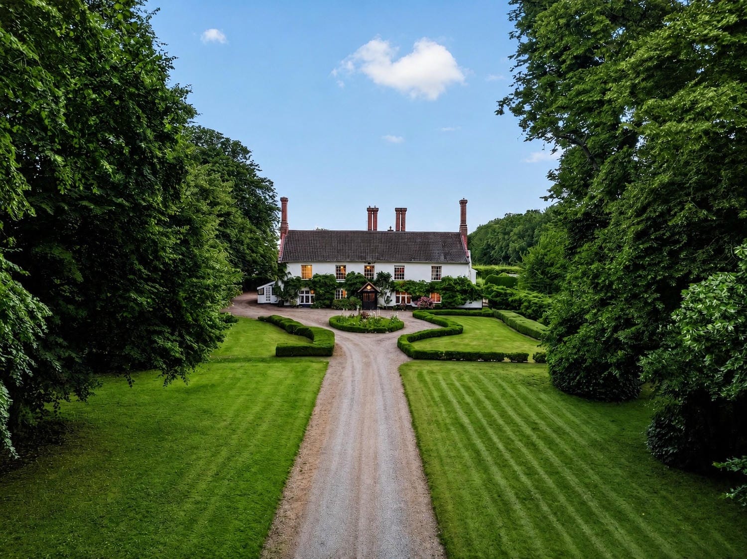 Aerial view of Bury's Hall with formal gardens and tree-lined drive