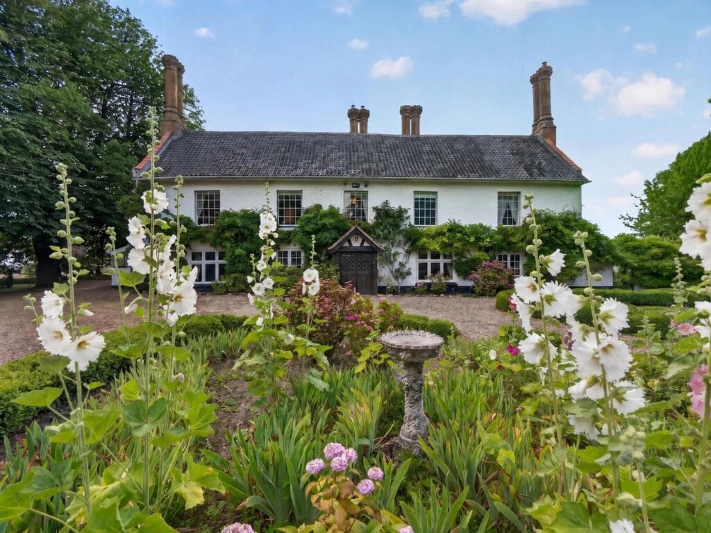 Bury's Hall Ashill rear garden with hollyhocks and stone birdbath