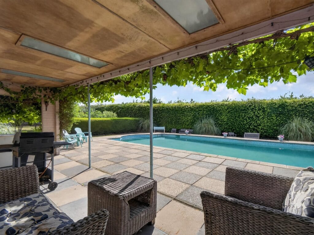Covered poolside terrace with wisteria canopy and outdoor seating area