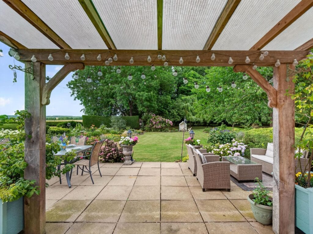 Covered pergola terrace with seating overlooking mature gardens