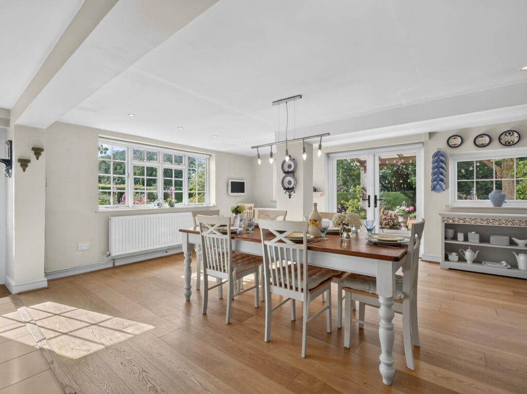 Bright dining room with oak flooring and large windows overlooking garden