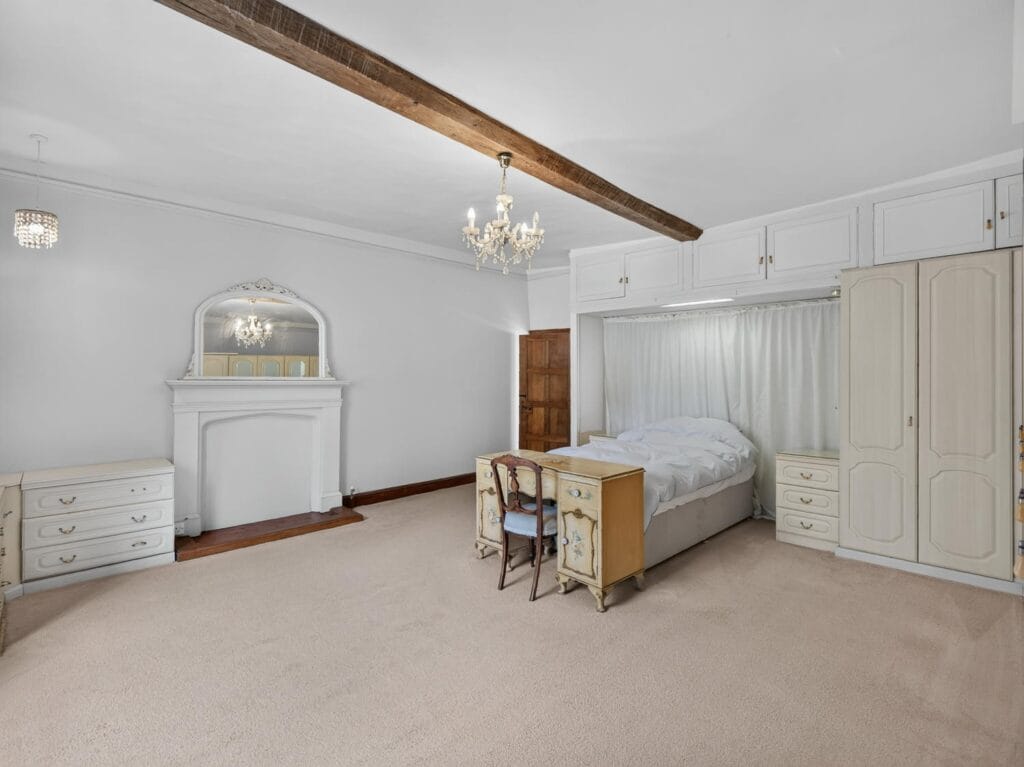 Light-filled bedroom with ornate fireplace and fitted wardrobes