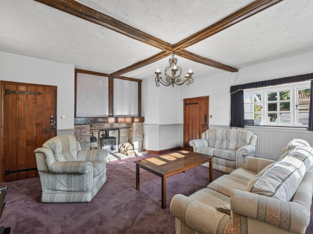 Beamed sitting room with fireplace, chandelier and traditional sofas