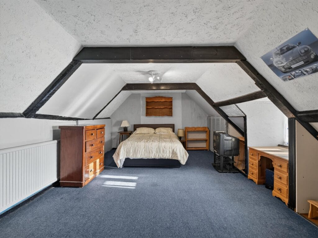 Vaulted bedroom with exposed beams, double bed and blue carpet