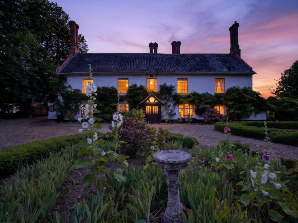 Bury's Hall Ashill manor house facade at sunset with cottage garden