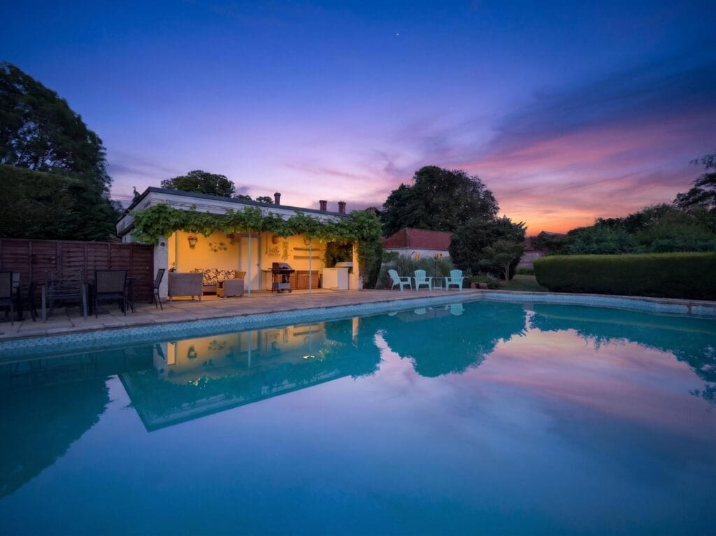 Bury's Hall Ashill outdoor pool at twilight with glowing poolhouse