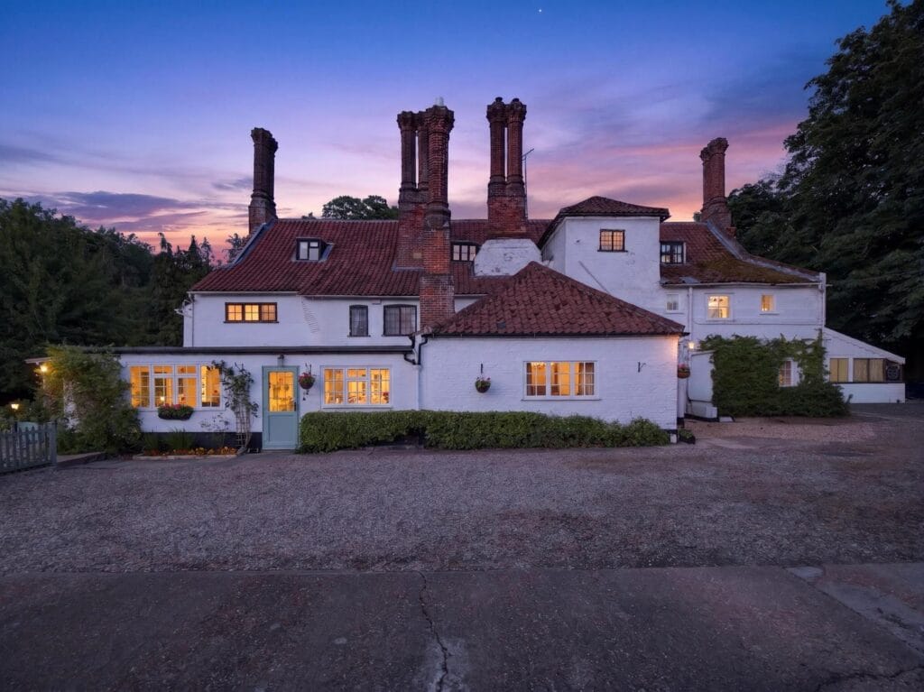 Twilight front elevation of Bury's Hall showing iconic twin chimneys
