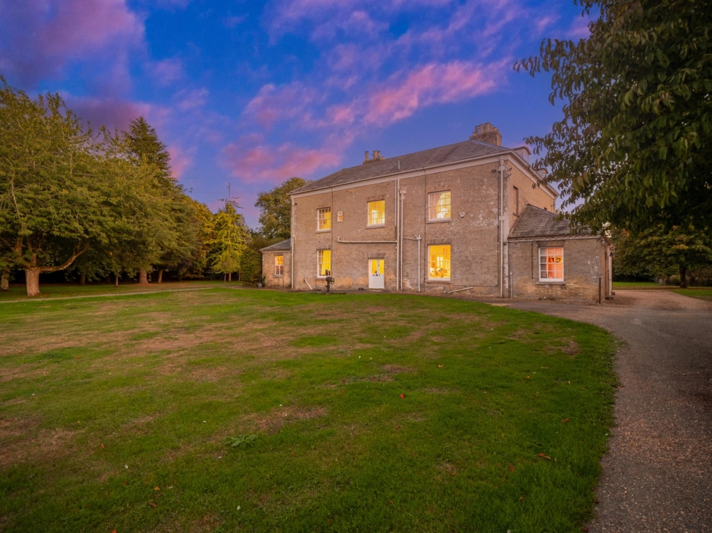 Loddon Hall rear and side elevation at dusk across lawn and drive, Norfolk