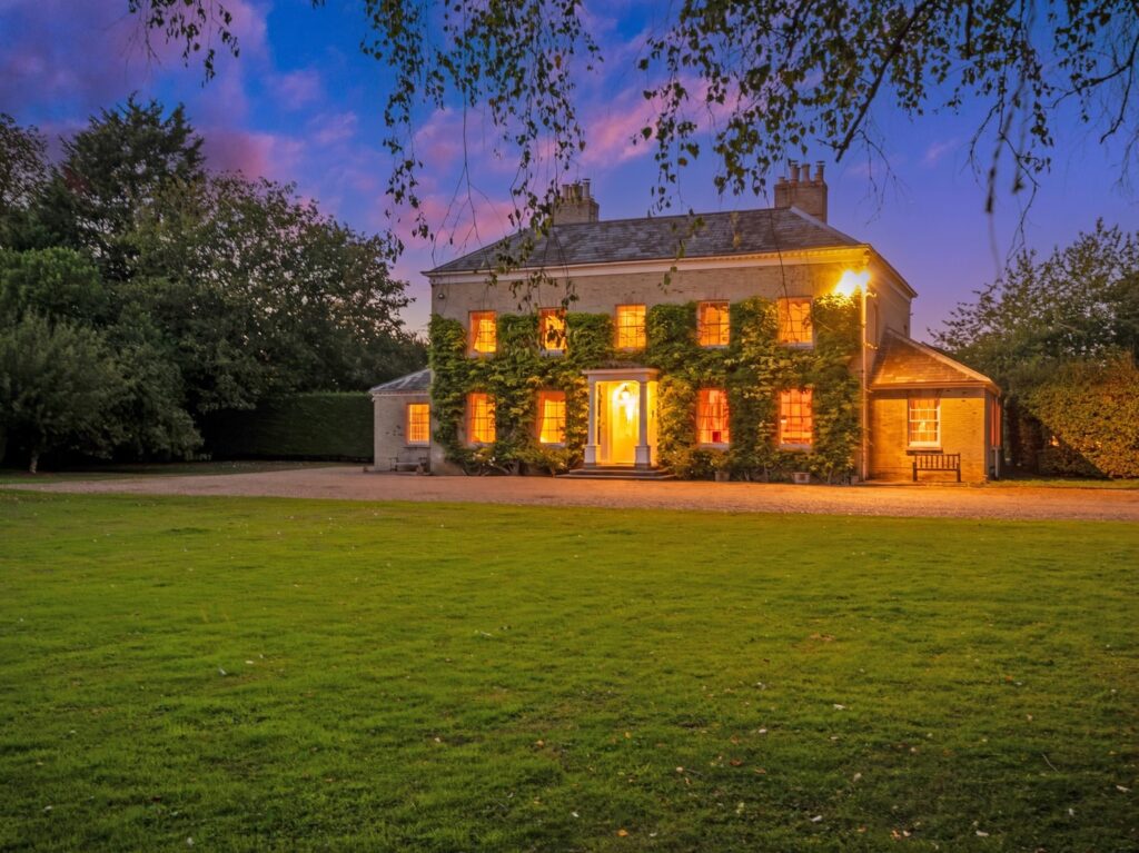 Loddon Hall at dusk, ivy-covered Georgian country house with illuminated windows, Norfolk