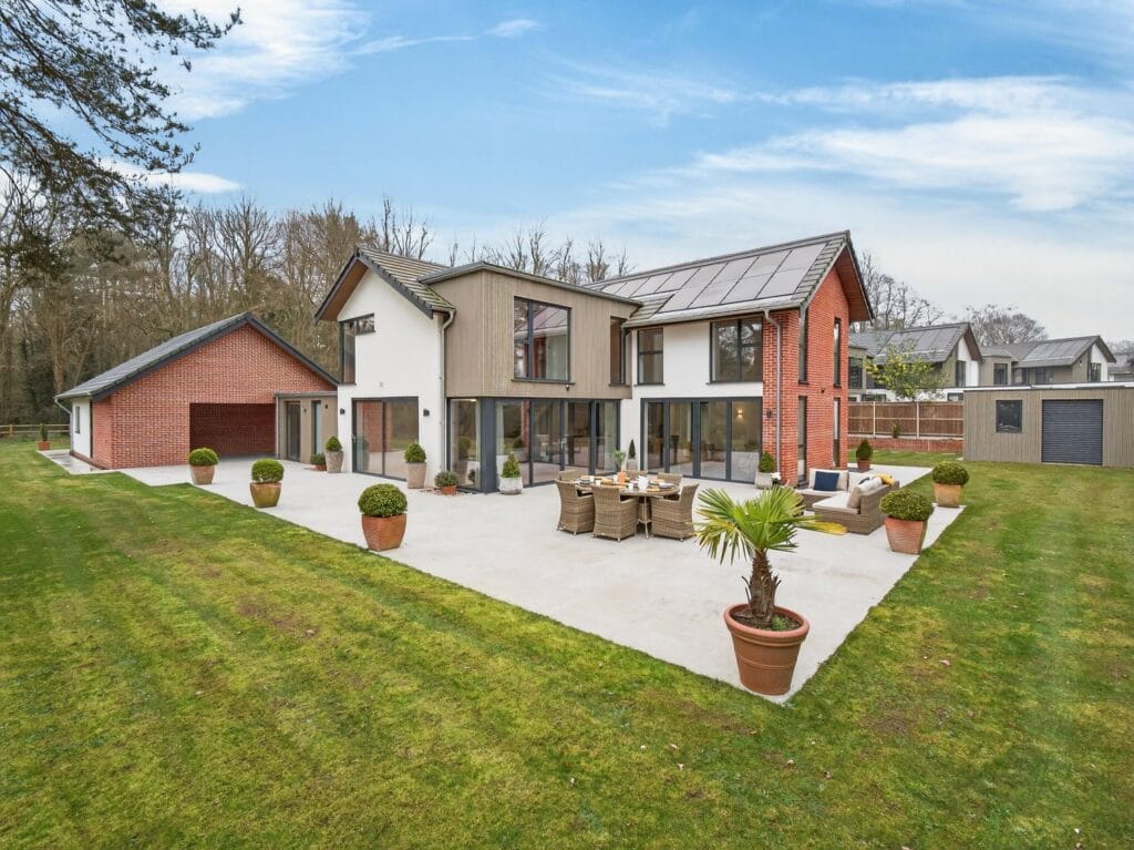 Contemporary architect-designed luxury home with large patio terrace, landscaped garden and detached double garage.