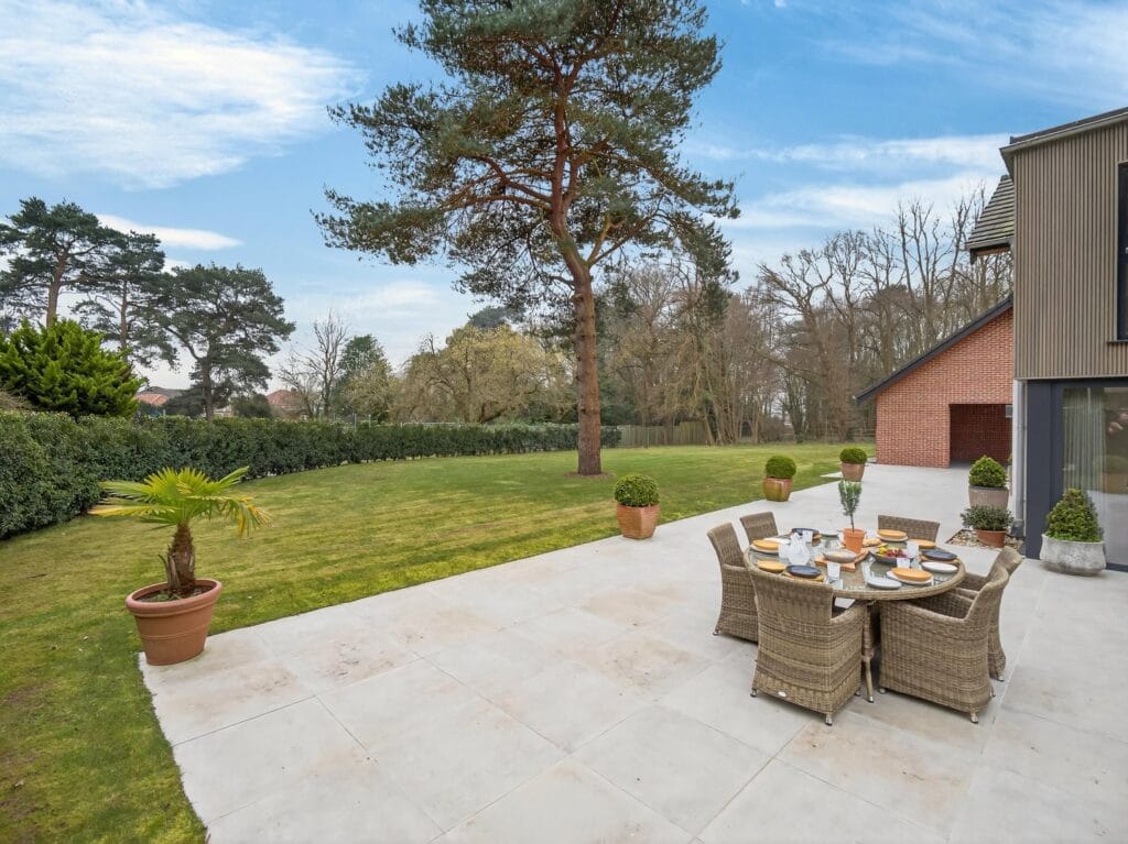 Large garden and patio terrace with outdoor dining area beside the contemporary luxury home.
