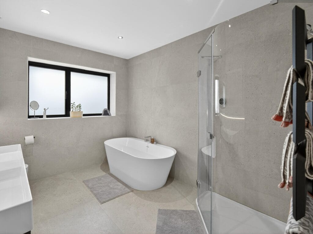 Modern family bathroom with freestanding bath, walk-in shower, contemporary tiling and frosted window.