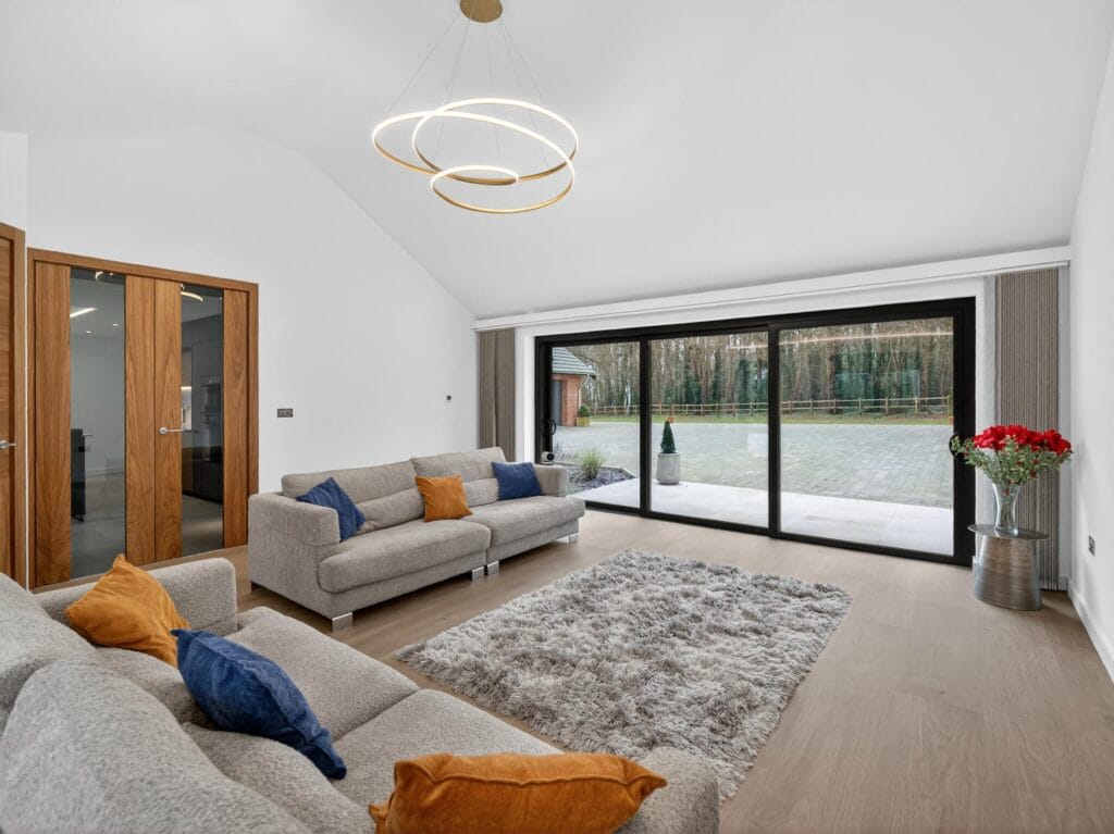 Modern media lounge with vaulted ceiling, contemporary lighting and large sliding doors to the patio