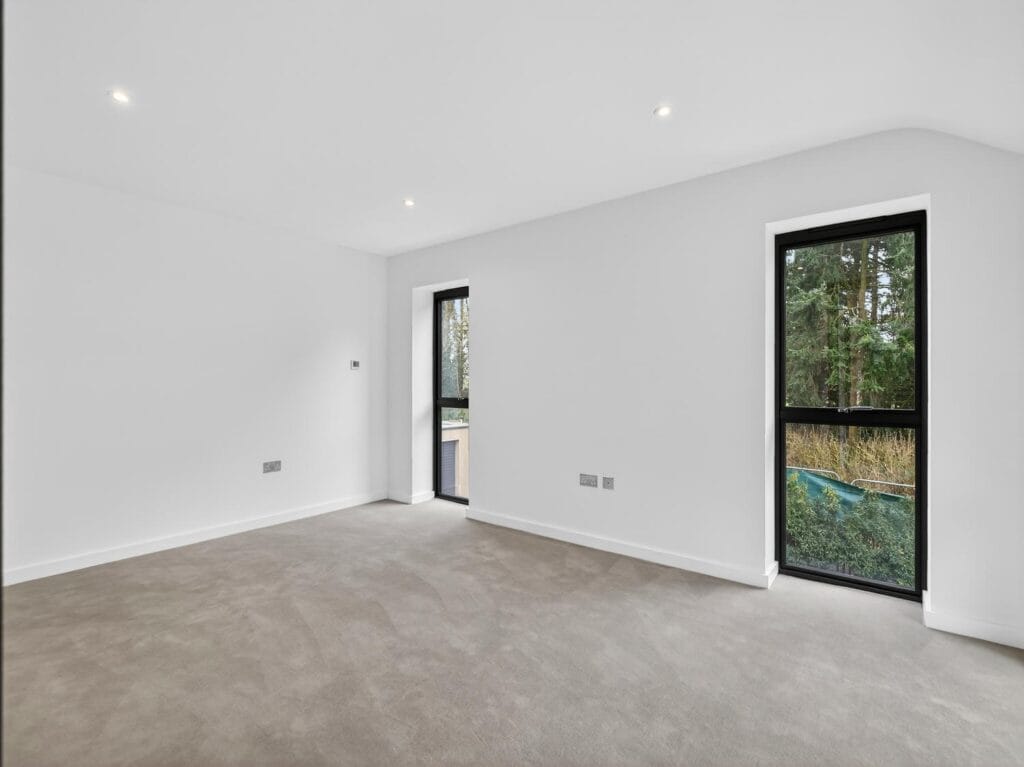 Bright double bedroom with large windows, neutral décor and views across the garden.