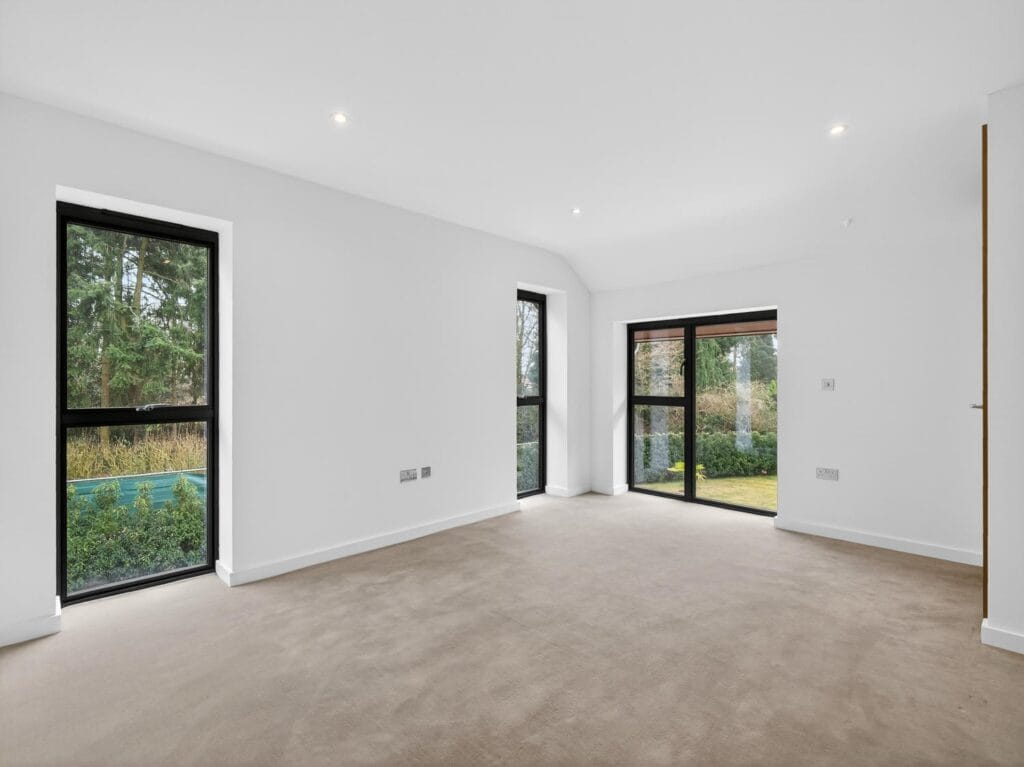 Spacious double bedroom with large windows, garden views and contemporary neutral décor.