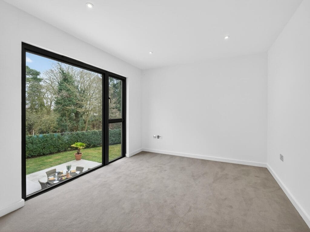 Modern double bedroom with large picture window and views over the landscaped garden and patio.