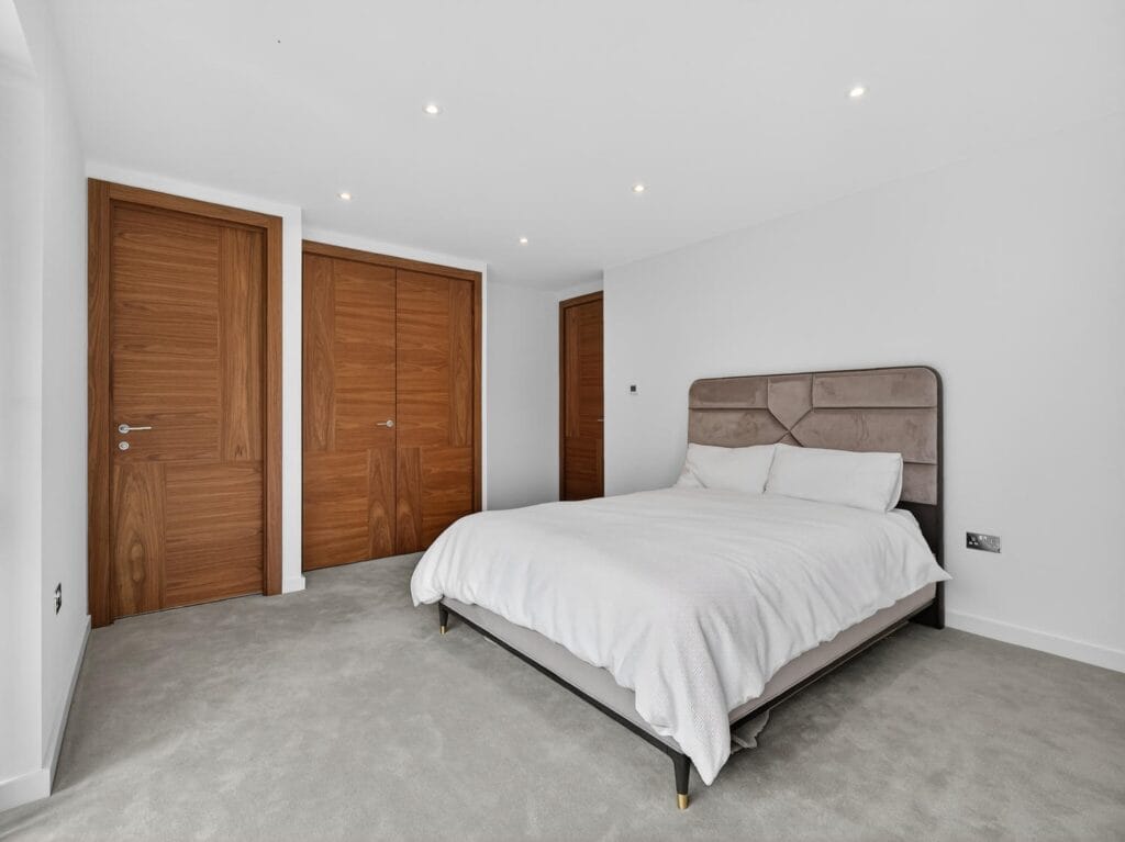 Modern double bedroom with built-in wardrobes, soft carpet flooring and contemporary neutral décor.
