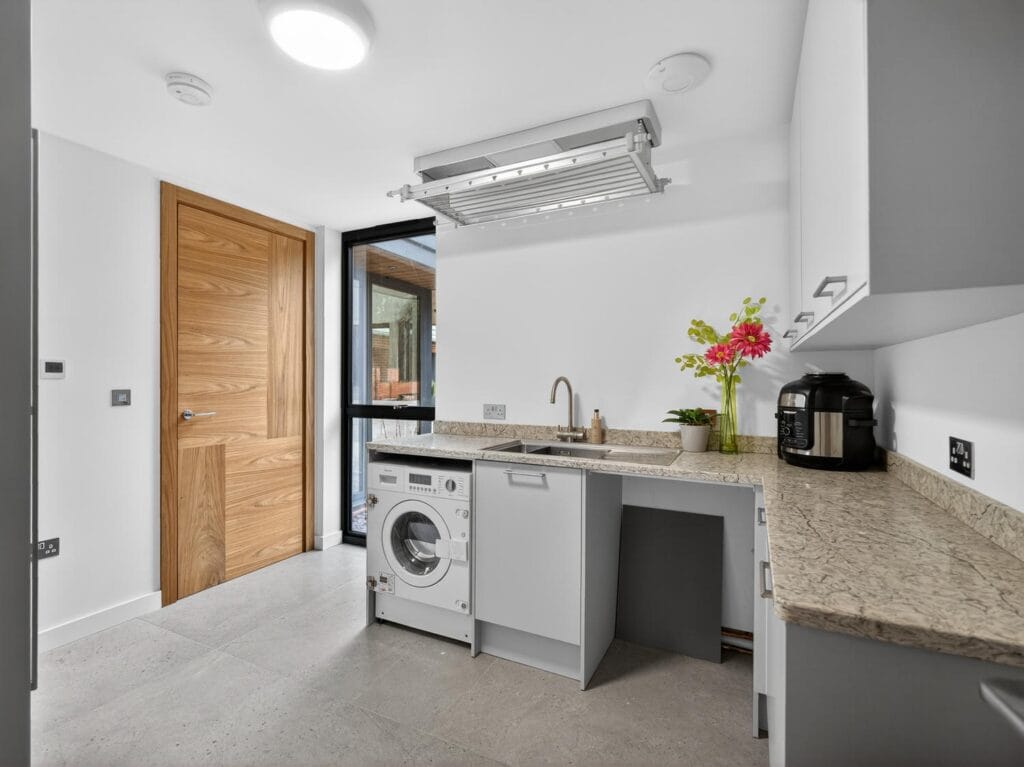 Modern utility room with sink, worktop space, washing machine and storage cabinets.